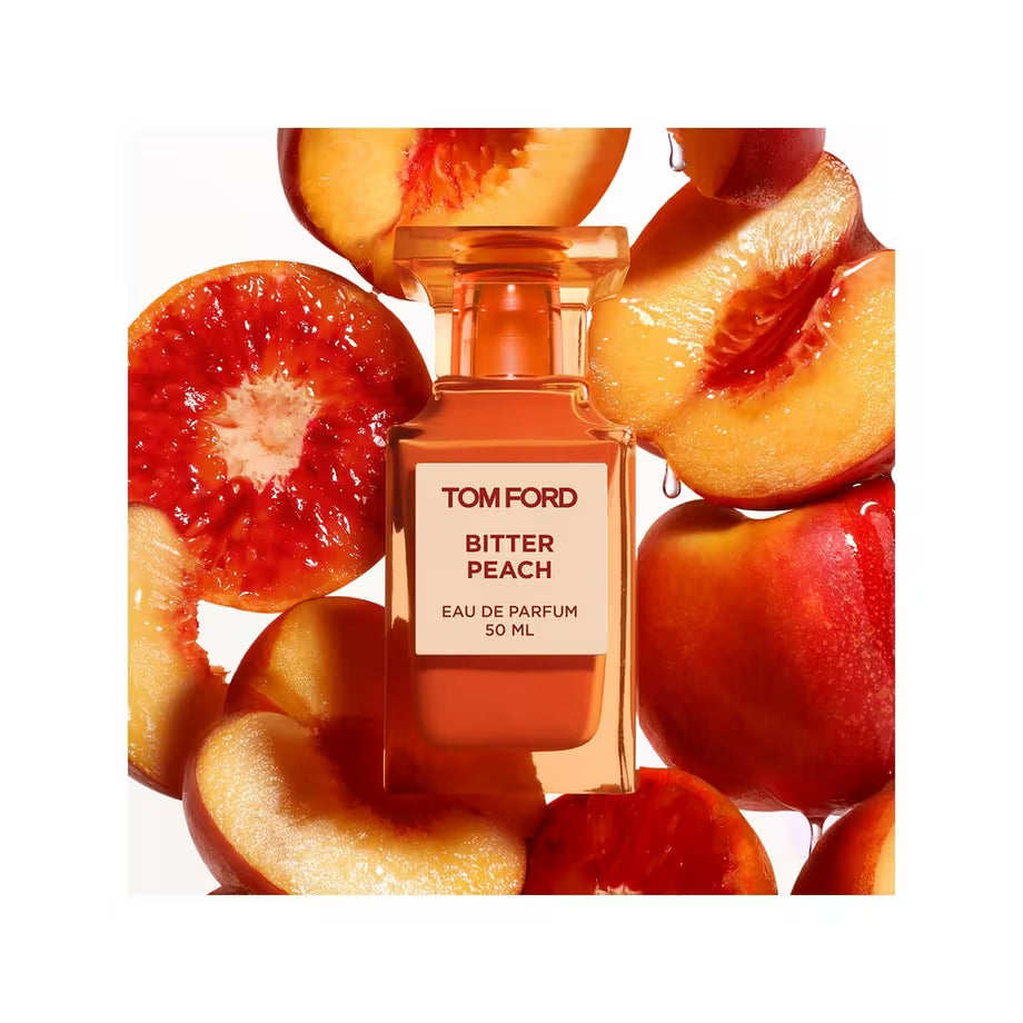 Tom Ford Bitter Peach Eau de Parfum im orangefarbenen Flakon zwischen aufgeschnittenen Pfirsichen.