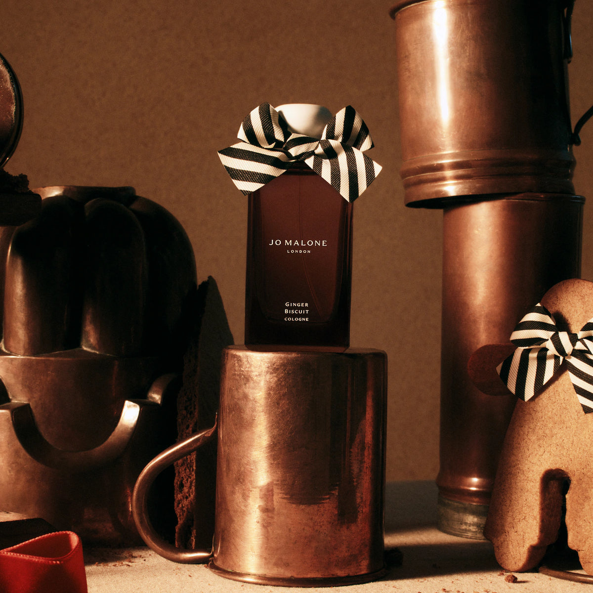 Jo Malone Ginger Biscuit Cologne with a striped bow on a copper mug.