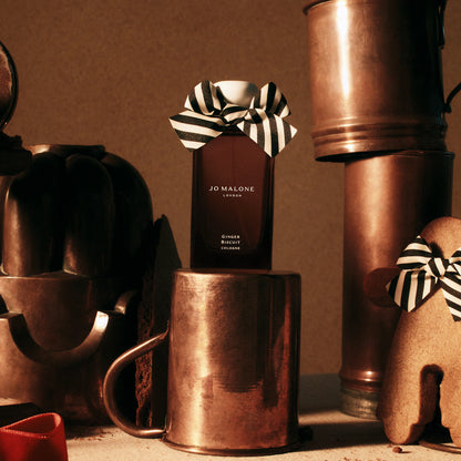 Jo Malone Ginger Biscuit Cologne with a striped bow on a copper mug.