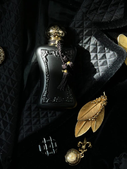 Parfums de Marly Athalia Eau de Parfum on black fabric beside gold jewellery.