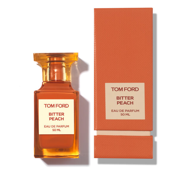 Tom Ford Bitter Peach Eau de Parfum im orangefarbenen Flakon neben der passenden Verpackung.
