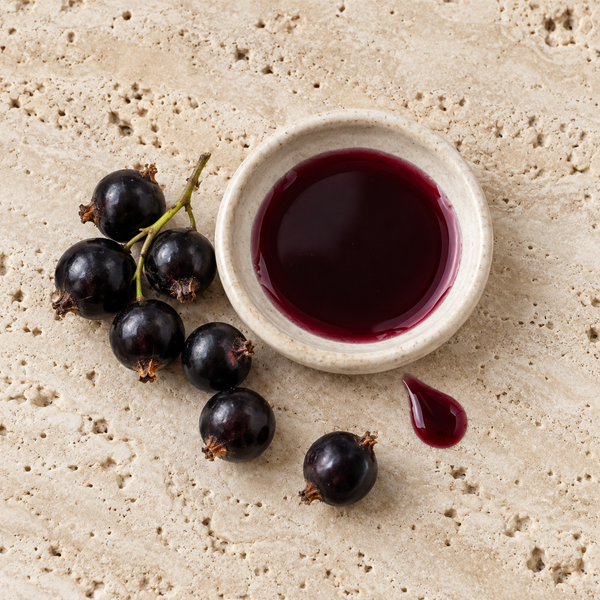 Blackcurrants beside dark blackcurrant syrup