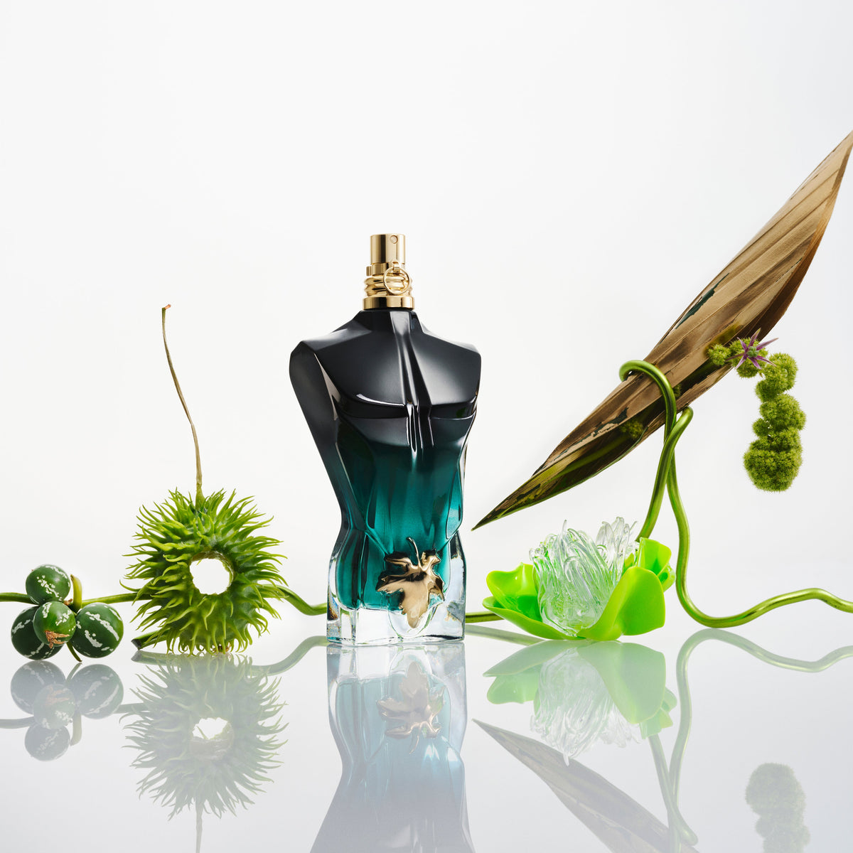 Jean Paul Gaultier Le Beau Le Parfum: flacone tra piante e foglie verdi.
